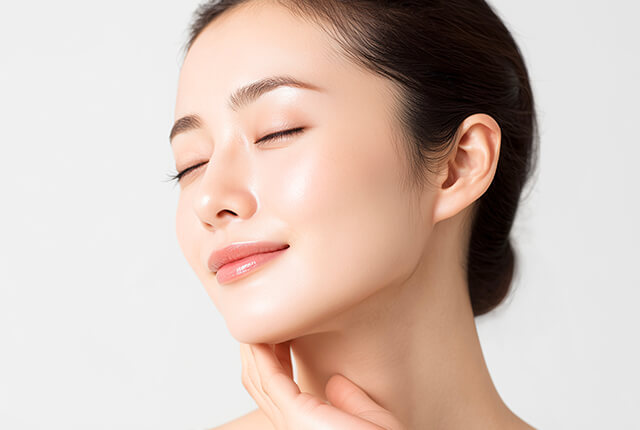 右手を首に当てて微笑む女性